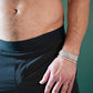 Close-up of a person wearing six tennis bracelets and a gold ring
