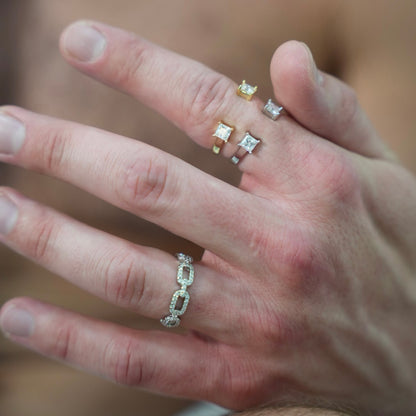 Hand wearing multiple diamond rings with a blurred background